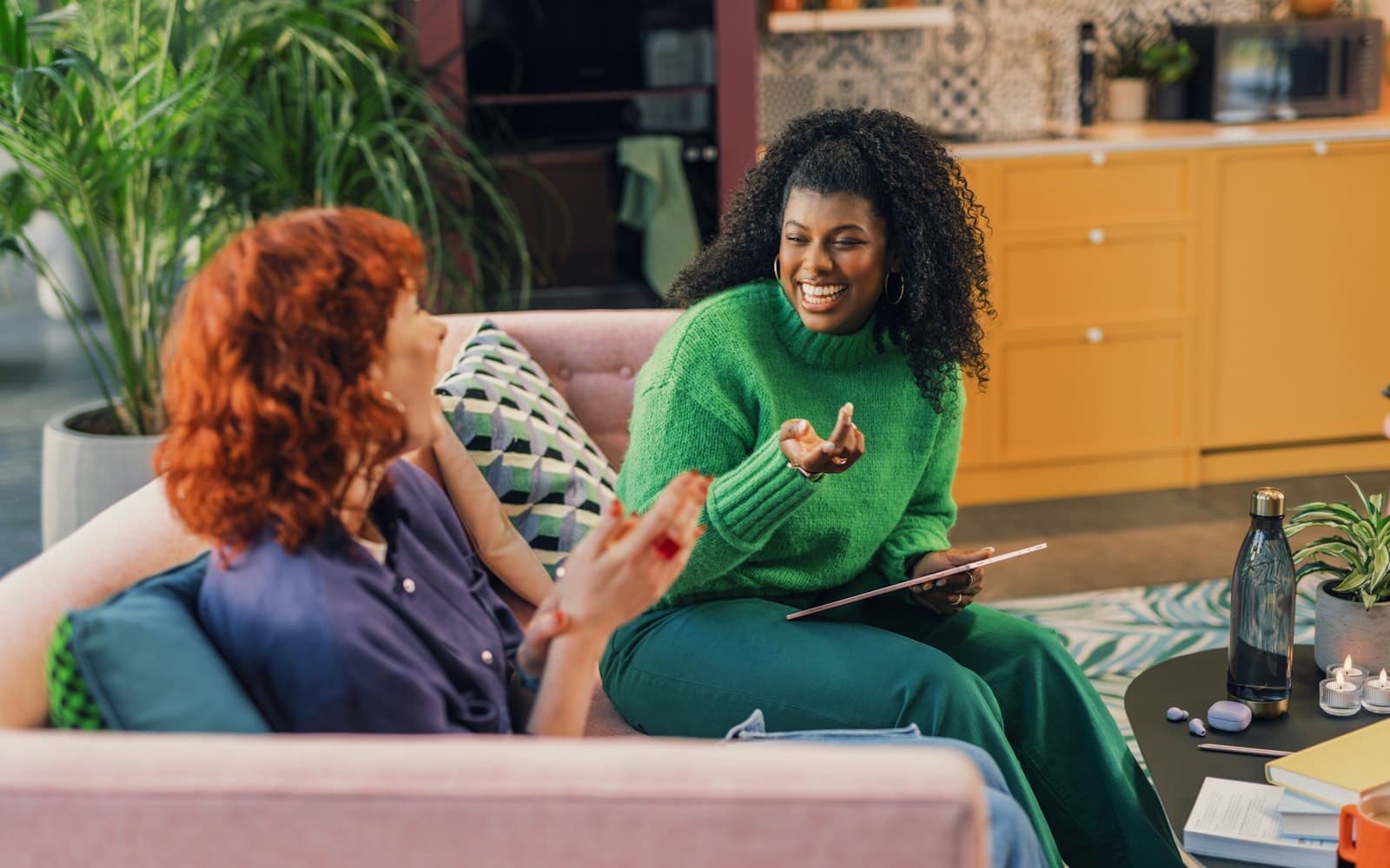 Kanepede oturup gülüşerek sohbet eden iki kadın