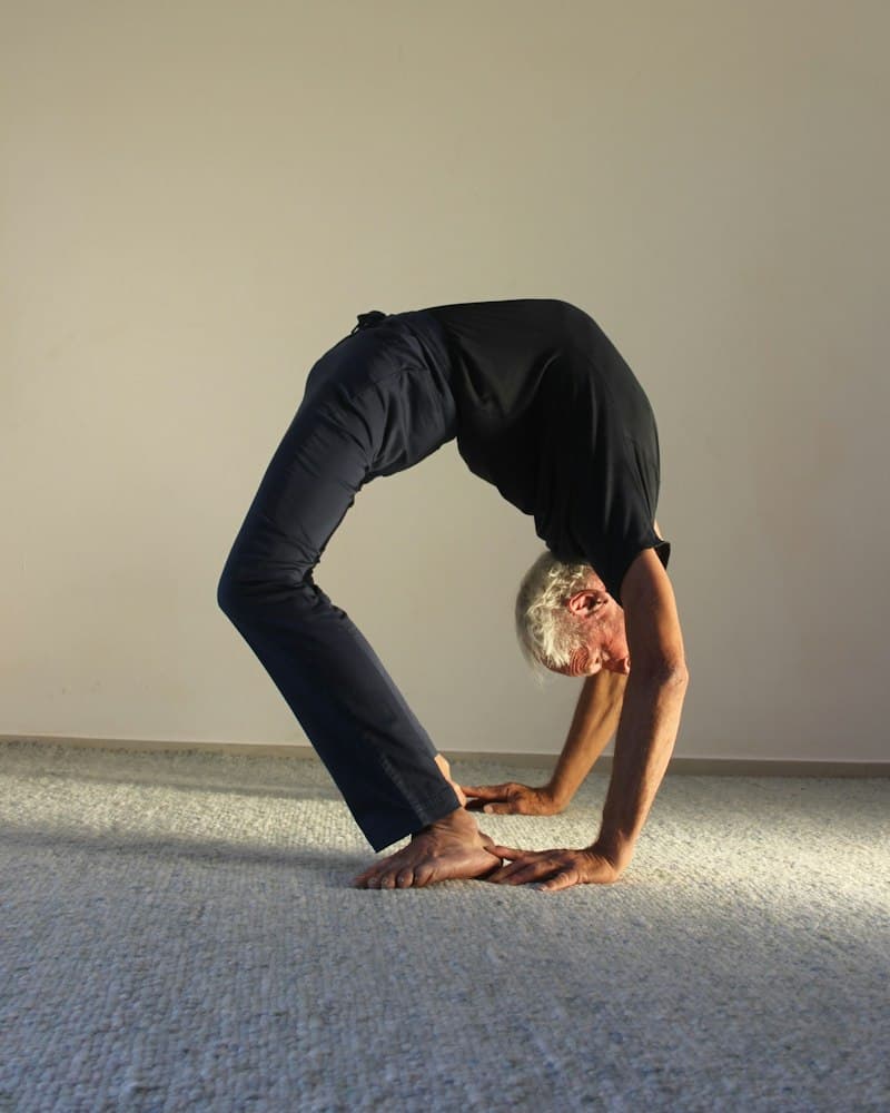 Köprü pozunda yoga yapan gri saçlı bir adam